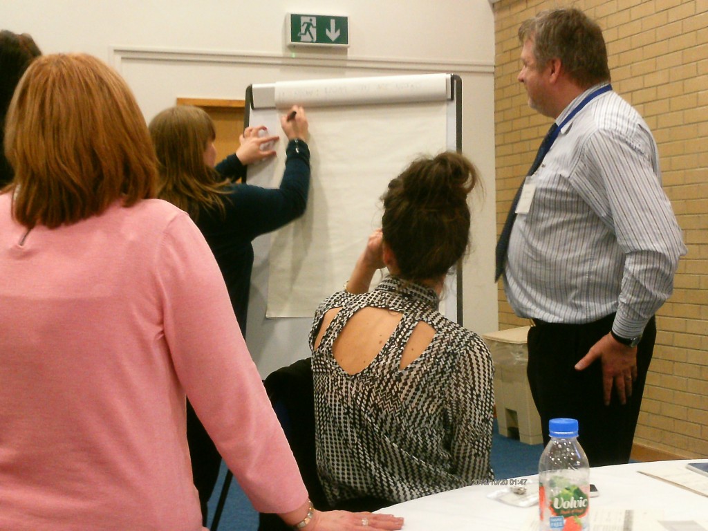 Delegate writes on board as colleagues look on