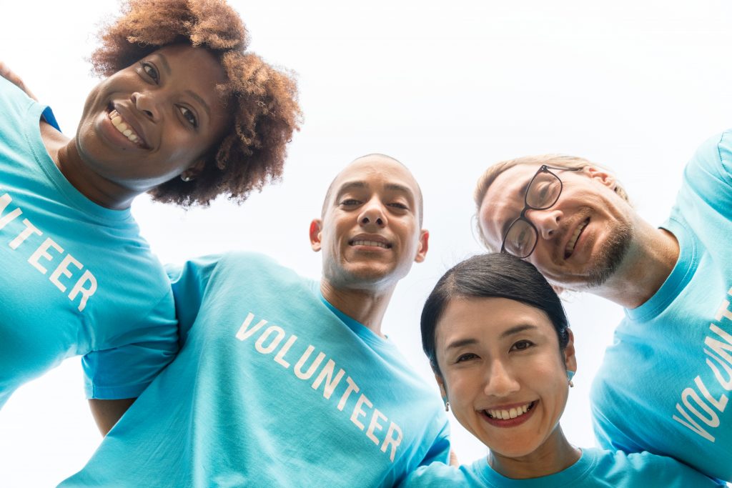 4 people wearing volunteering tshirts looking down