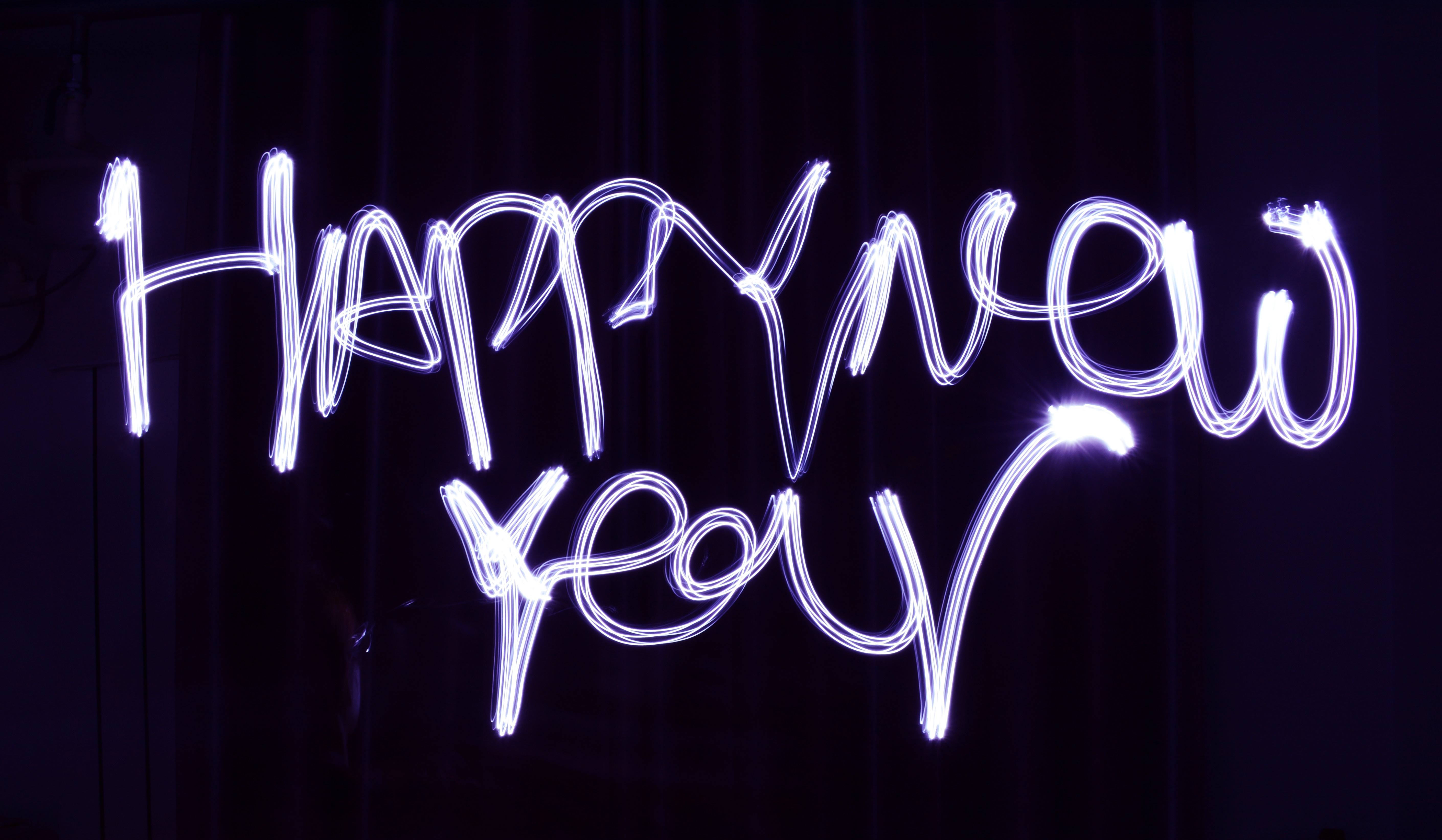 The words "Happy New year" written with a purple sparkler on a black background