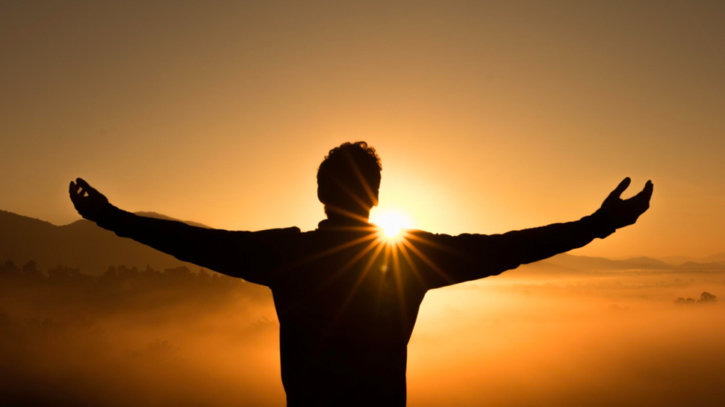 Person arms outstretched  in sunset