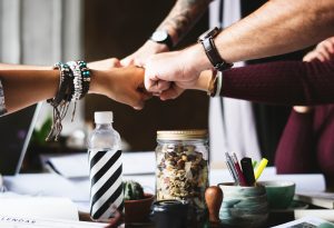 Five hands doing a fist bump over a desk.