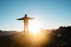 image of a man standing on a hill in the sunshine 