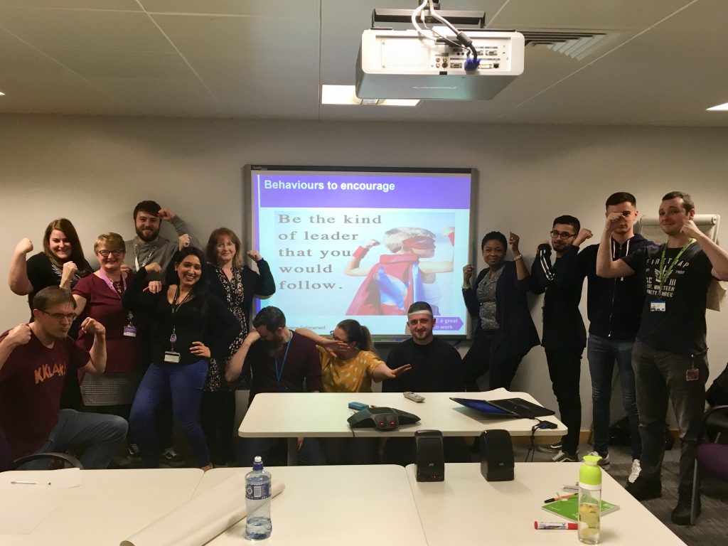 a groupf o emerging leaders in front of a screen showing the words "Be the kind of leader that you would follow"