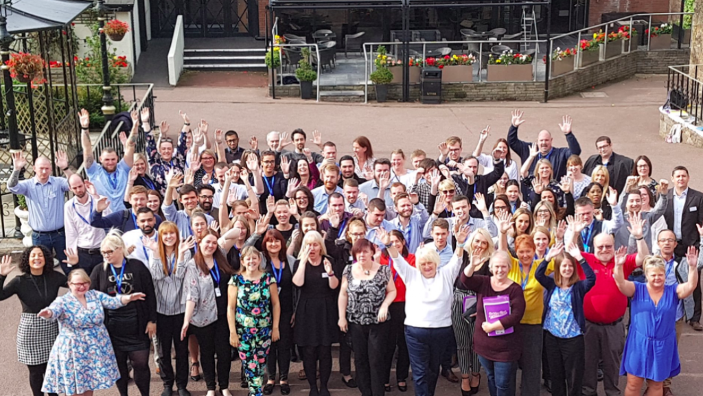 Large group of academy delegates waving up at camera