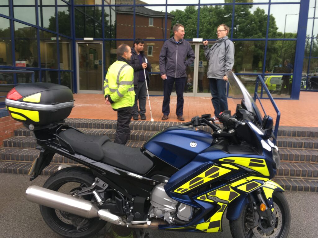 4 people standing and looking at a motorbike