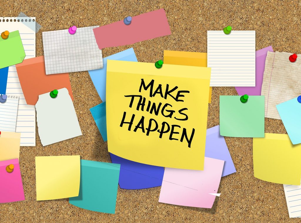 Bulletin board with post its and middle one saying make things happen