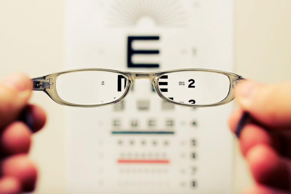 A PAIR OF SPECTACLES IN FRONT OF AN EYE SIGHT TEST BOARD