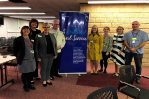 A group of smiling people standing beside the 'Brilliant Civil Service' banner.