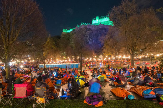 groups of people in sleeping bags in Princes street gardens Edinburgh with the castle overlooking them