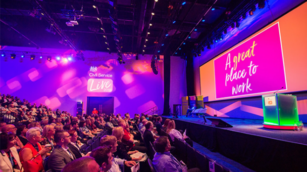 Audience sitting and facing a stage where there is big screen with A great Place to work written on it. 