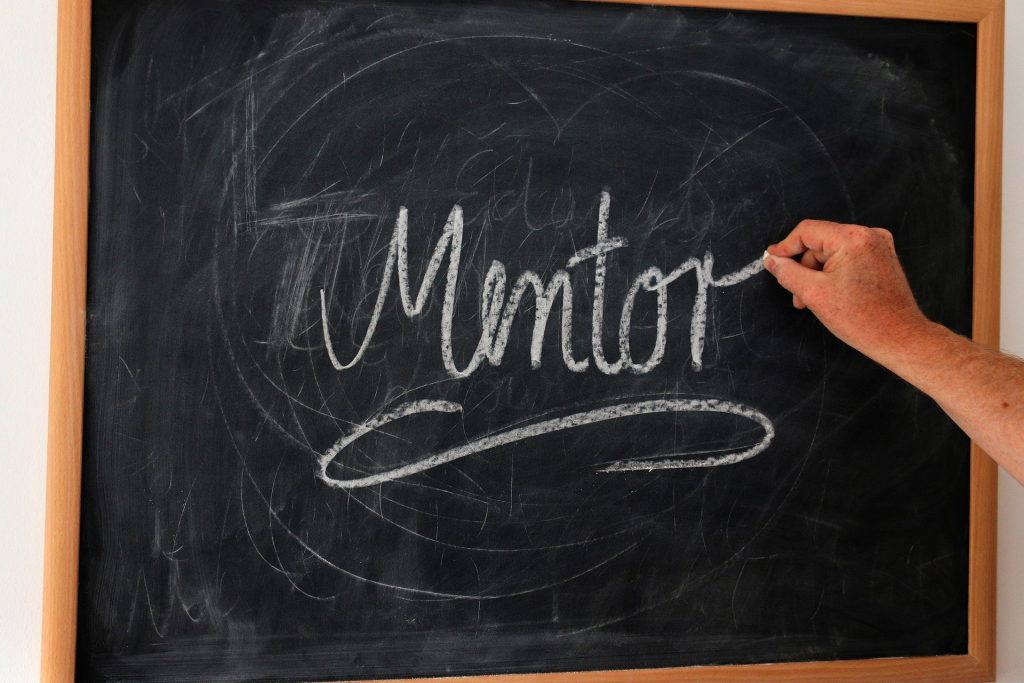 Chalk board with hand writing the word 'mentor'