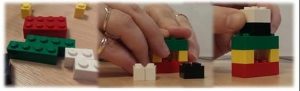 A pair of hands building with lego blocks