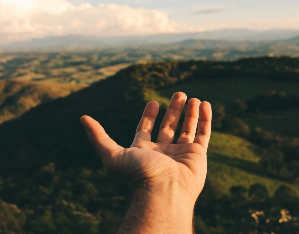 Hand reaching out towards blue sky