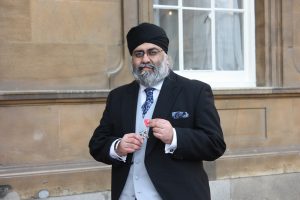 MR Amrik Singh Bahbra holding a MBE honour medal