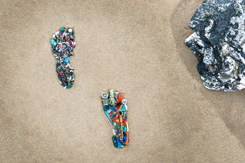 beach with plastic waste in the shape of feet